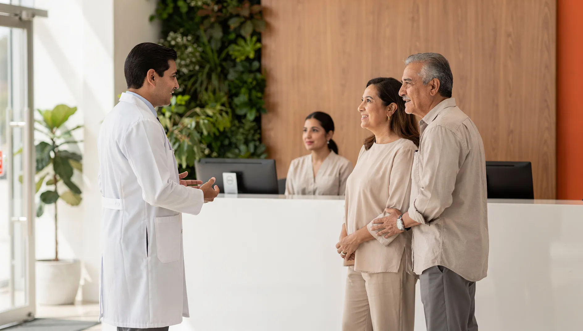 Médico de Neurocenter recibiendo a una pareja de pacientes en la recepción